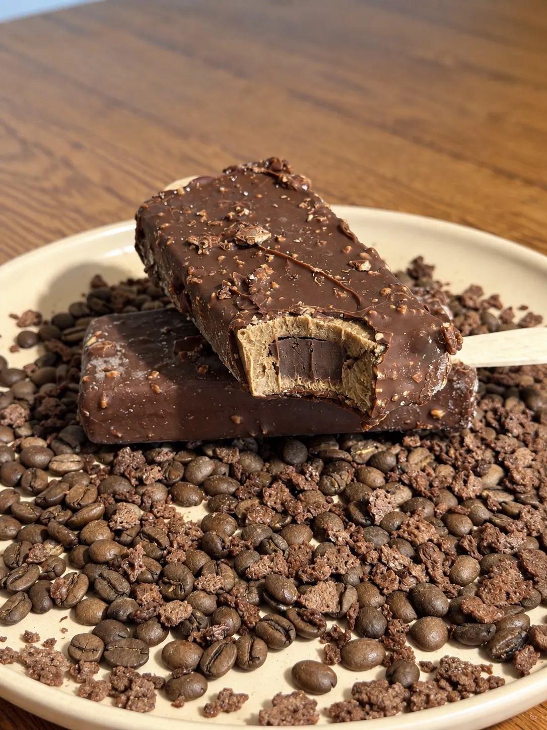 Paleta Coffe Malte mordida, com recheio de chocolate, sobre grãos de café
